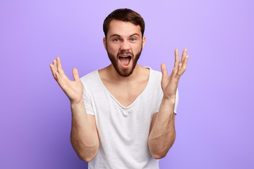 Fototapeta premium funny man with raised hands shouting at somebody, screaming. man singing a song, isolated blue background. studio shot
