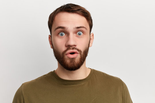 shocked emotional man with bugged eyes and rounded mouth looks at the camera , being amazed to see something unexpected.feeling and emotion, isolated white background