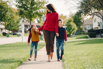 Cute family in a autumn park. Happy mother with two children. Family in the courtyard near the house.
