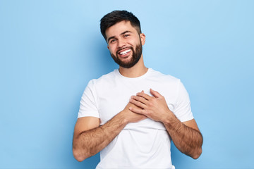 happy overjoyed hipster guy smiles happily, keeps hands on heart, expresses pleasant emotions...
