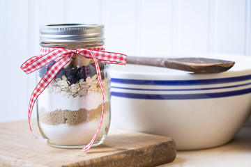 Original photograph of a cookie mix in a jar ingredients with baking utensils on white