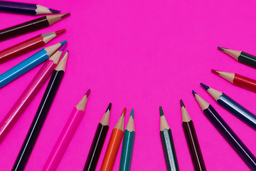 Many colored pencils lie on a pink background. Copy spase. The concept of back to school, the educational process, study at school, drawing