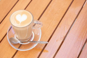 Delicate cappuccino in a transparent cup with a heart on a foam