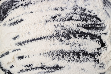 Flour texture. White flour on dark table. Baking background. Top view, copy space