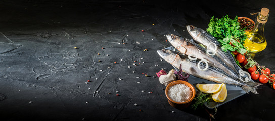 Fresh raw herrings with herbs, spices, onion and parsley on dark background. Top view with copy...