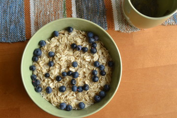 oatmeal with fresh blueberries. organic cereals in the green bowl on the wooden background. vegan breakfast.