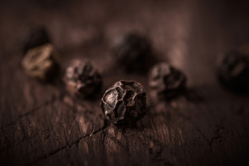 black pepper grains on wooden background close-up
