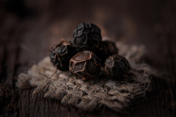 grains of black pepper on jute fabric close-up