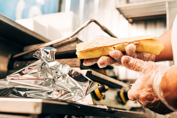 partial view of cook in gloves using aluminium foil while preparing doner kebab