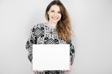 Young woman with mockup poster on grey background.