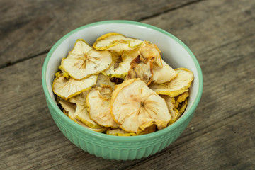 Apple chips in a green bowl wooden background