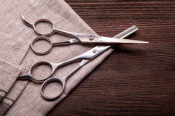 Hairdressing scissors on a black wood background.
