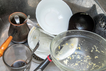 Dirty dishes in the sink. Dirty cook, turk, cup, bowl, spoons in  sink