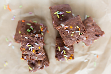 Banana brownies with multi colored sprinkles, crinkled parchment paper, wooden background