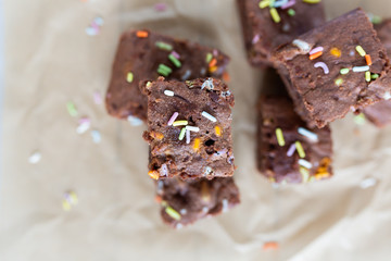 Banana brownies with multi colored sprinkles, crinkled parchment paper, wooden background