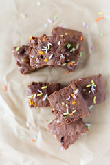 Banana brownies with multi colored sprinkles, crinkled parchment paper, wooden background