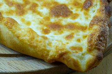 Freshly baked khachapuri with cheese on a wooden board.