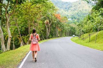 Beautiful Rain forest with a young woman traveler on the road into the forest Thailand. Female walks on a rain forest road and enjoys the views of nature