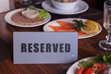 Restaurant reserved table sign with places setting and wine glasses ready for a party