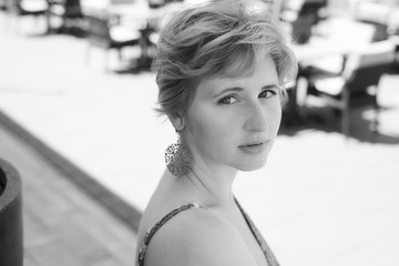 black and white portrait of young woman with short blonde hair, sitting on terrace