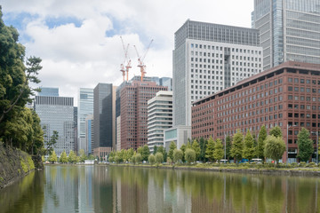 Urban background with Tokyo downtown Marunouchi business district city scape and water reflections of trees and buildings in summer day illustration urban and ecology concept.