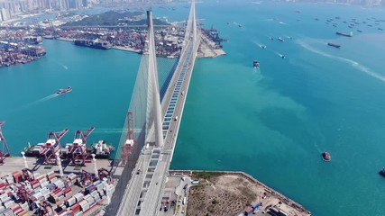 Aerial shot of large cable stayed Stonecutters bridge, span across turquoise waters of Rambler Channel. Modern highway at Hong Kong, part of Lantau Link project. Container terminal facilities seen