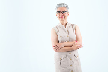 Beautiful mature woman in glasses on a light blue background. Female middle age with gray hair.