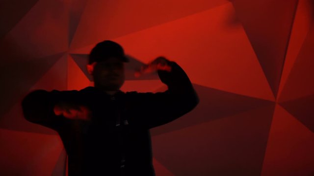 Rapper man dancing to the music. Silhouette on a dark red background