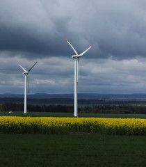 Field of oilseed rape and wind power station in czech republic. Rapeseed is everywhere. Ecological electric power. Replacement for coal-fired power station