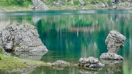 Fototapeta na wymiar Berge und Bäume spiegeln sich im grünen Karersee in Südtirol