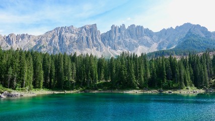 Berge und Bäume spiegeln sich im grünen Karersee in Südtirol
