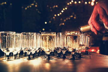 Man pouring wine in the glass on holiday table in night-time lighting.