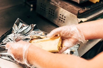 partial view of cook in gloves using aluminium foil while preparing doner kebab
