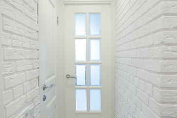 White classic doors and white decorative brick wall.