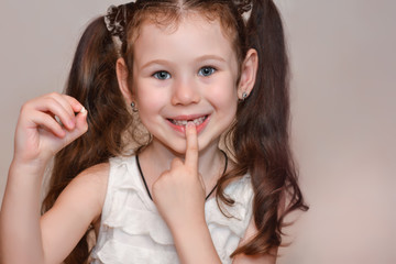 Girl 6 years old holds a tooth in her hand, which she lost