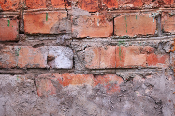 Weathered terracota brick wall with cement and cracks