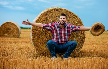 Naklejka na ściany i meble Happy farmer in a wheat field after the harvest. Agricultural concept