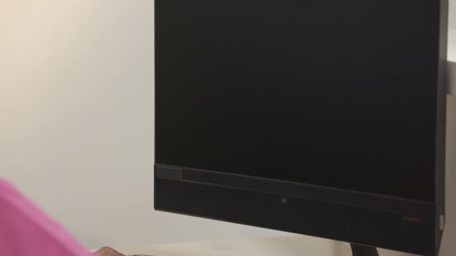 Camera tilt up from nurse fingers typing to blank computer screen