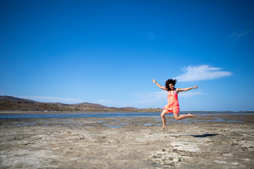 Jumping red dress woman at beach