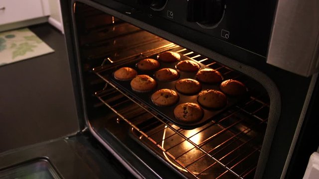 Tilt up of muffins being removed from oven