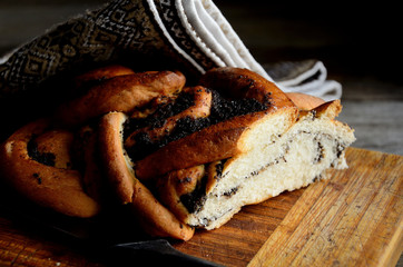 Bread with poppy seeds, a knife on a folk napkin on a rustic table. Holiday Macovei.