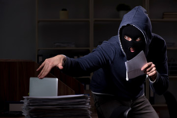 Male thief in balaclava in the office night time