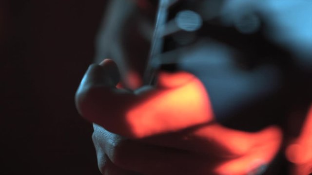 A guitarist performing bass party on electric fretless bass guitar slowly turns around under warm lighting, with smoke