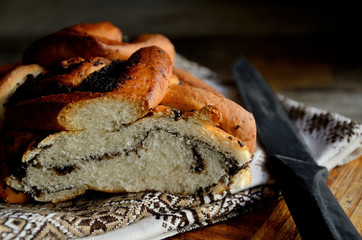 Bread with poppy seeds, a knife on a folk napkin on a rustic table. Holiday Macovei.