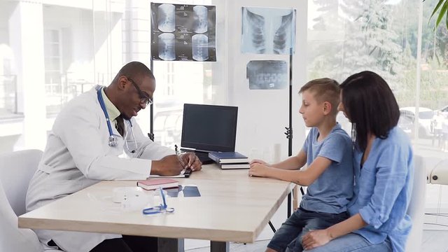 African young doctor giving prescription to cute mother with here son at clinic.
