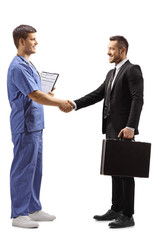 Fototapeta premium Young male doctor in a blue uniform shaking hands with a businessman