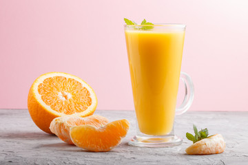 Glass of orange juice on a gray and pink background. Side view