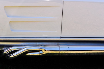 Close-up of a Sports car's left side chrome side exhaust pipe