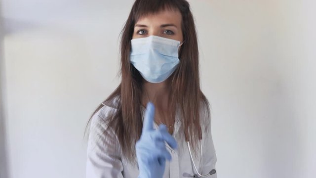 Young doctor woman warning you about a bad habit. Doctor in medical masks haking her finger.