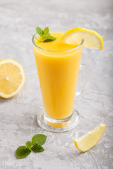 Glass of lemon drink on a gray concrete background. Side view